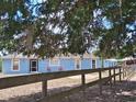 Single-story home with light blue exterior, framed by trees and a wooden fence, offers privacy and charm at 25618 Fishermans Rd, Paisley, FL 32767