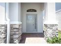 Inviting covered entry featuring stone pillars and a light gray front door with transom window and brick paving at 4548 Dulwik Pl, Sanford, FL 32771