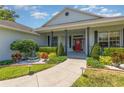 Inviting front porch with colorful flowers, attractive landscaping, and a striking red front door with wreath at 5494 Glen Oak Pl, Sanford, FL 32771