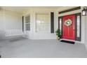 Charming covered front porch with swing, complemented by a red front door with decorative wreath at 5494 Glen Oak Pl, Sanford, FL 32771