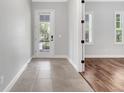 Hallway with tile flooring leading to a bedroom with hardwood floors and natural light at 13662 Behring Ave, Orlando, FL 32827