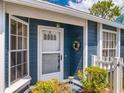 Inviting front entrance featuring a glass storm door, wreath, and trimmed bushes at 148 Meadow Blvd, Sanford, FL 32771