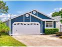 Two car garage with a white garage door and a well-manicured lawn with hedges and a tree at 148 Meadow Blvd, Sanford, FL 32771