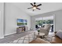 Well-lit living room with modern gray floors, ceiling fan, and sliding doors to the outside patio at 1527 Braewick St, Winter Springs, FL 32708