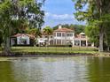 Scenic backyard view from the water, showing a beautiful home with a terracotta roof and expansive lawn at 1640 E Adams Dr, Maitland, FL 32751