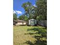 View of a charming backyard shed with double doors, surrounded by a lush green lawn and mature trees at 1872 N Akron Dr, Deltona, FL 32738
