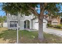 Two-story home with attached two-car garage, a large tree, and well-maintained landscaping at 2806 Polson Dr, Kissimmee, FL 34758