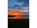 Reflective sunset over water, viewed from a property's grassy backyard with a black fence at 2926 Wordsmith Rd, Kissimmee, FL 34746
