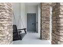 Inviting front porch featuring stacked stone columns and a relaxing porch swing. Welcome Home! at 7605 Lake Hancock Blvd, Winter Garden, FL 34787
