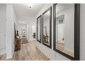 Bright hallway with wood floors, white walls, and decorative mirrors leading to other rooms at 849 Avenal Ln, Davenport, FL 33837