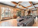 Spacious living room with exposed wood beams, tile flooring, and a large comfortable sectional at 9730 Lounsberry Cir, Golden Oak, FL 32836