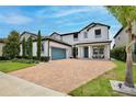 Attractive two-story home featuring a brick driveway, manicured landscaping, two-car garage, and covered porch at 10139 Austrina Oak Loop, Winter Garden, FL 34787