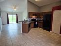 An open kitchen features wood cabinets, breakfast bar and black appliances with view into the living area at 119 Stewart Lake Loop, Groveland, FL 34736