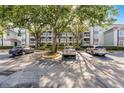 Exterior of a condo building with a parking lot featuring multiple cars and trees at 13839 Fairway Island Dr # 1116, Orlando, FL 32837