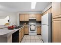 A view of a kitchen with light wood cabinets, white appliances and tile flooring at 13839 Fairway Island Dr # 1116, Orlando, FL 32837