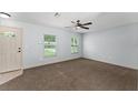 Spacious living room featuring plush carpet flooring, a ceiling fan, and bright windows at 14878 Se 32Nd Ter, Summerfield, FL 34491