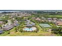 Aerial view of a community with a pool, a tennis court, ponds, and mature trees at 15242 Heron Hideaway Cir, Winter Garden, FL 34787