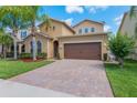 Inviting home features a two-car garage, paver driveway and a well-maintained lawn with lush landscaping at 15443 Sugarcup Ct, Orlando, FL 32828