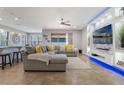 Modern living room with a large gray sectional, tile flooring, and entertainment center with accent lighting at 15443 Sugarcup Ct, Orlando, FL 32828