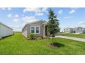 A green lawn with a young tree out front enhances the curb appeal of this home at 2009 Stone Wall Ct, Lake Hamilton, FL 33851