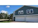 View of two-story townhomes with individual garages, set against a clear blue sky with fluffy white clouds at 222 Glass Onion Dr, Groveland, FL 34737