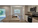 Modern kitchen with stainless steel appliances and granite countertops overlooking the dining area at 222 Glass Onion Dr, Groveland, FL 34737