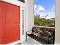 Inviting front porch featuring a vibrant red door and charming welcome bench at 232 Oxford Rd, Davenport, FL 33896