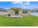 Cozy backyard featuring a covered patio with a dining set, green grass, and white fencing at 2815 Shelburne Way, St Cloud, FL 34772