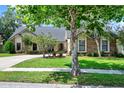 Charming brick home with mature trees, well-maintained lawn, and a long driveway leading to the garage at 370 Brushwood Ln, Winter Springs, FL 32708