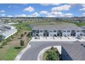 Aerial view of gray townhomes in a community overlooking a scenic pond and green spaces at 5214 Dragonfly Dr, Wildwood, FL 34785