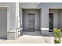 Close-up of the gray front door with a covered porch and well-maintained surroundings at 5214 Dragonfly Dr, Wildwood, FL 34785