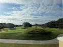 Scenic view of a lush green golf course with rolling hills and trees under a partly cloudy sky at 7518 Seven Eagles Way # 201, Reunion, FL 34747