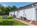 Side of house featuring a well-maintained lawn, convenient access door, and exterior utility connections at 825 White Birch Ct, Orange City, FL 32763