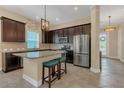 Modern kitchen featuring stainless steel appliances, granite countertops, dark cabinets, and an island with breakfast bar seating at 8679 Laureate Blvd, Orlando, FL 32827