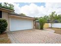 Attached two-car garage with white door and a brick paver driveway at 100 Crestwood Dr, Longwood, FL 32779