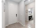 Bright foyer featuring neutral tile flooring, a white front door, and a glimpse of a half bath at 12335 Sumter Dr, Orlando, FL 32824
