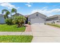 Inviting single-story home with a well-manicured lawn, palm trees, and a wide driveway leading to the garage at 12335 Sumter Dr, Orlando, FL 32824