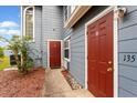 Close up of townhome entrance with red doors and unit numbers, nestled within landscaped mulch beds at 135 Orchid Dr, Davenport, FL 33897