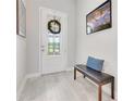 Bright foyer with a decorative front door, bench, and light wood-look tile flooring at 2127 Bay Line Rd, Oakland, FL 34787