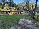 Tan single-story house with brown shutters and dark wood-colored doors and a lawn at 225 W 2Nd St, Chuluota, FL 32766