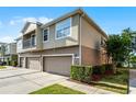 A townhome featuring a two-car garage and a side yard with lush landscaping at 3917 Pemberly Pines Cir, St Cloud, FL 34769