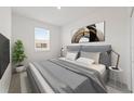 A stylish bedroom featuring a queen bed with a gray headboard, modern art, and a bright window at 555 Southern Edge Way, Sanford, FL 32771