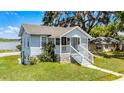 Charming exterior view of a light blue home with a welcoming front porch and manicured lawn at 730 S Main Ave, Groveland, FL 34736