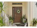 Inviting front entrance featuring a wreath-adorned door, complemented by potted plants and stylish seating at 889 Boxelder Ave, Minneola, FL 34715