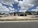 New home construction featuring a three car garage and modern architectural details under a cloudy sky at 960 Hawksnest Pt, Oviedo, FL 32765