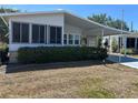 Welcoming home featuring a carport and sunroom, surrounded by green shrubs and a well-kept lawn at 158 Rita Bee Ave, Davenport, FL 33897