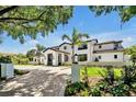 Elegant home featuring manicured landscaping and a circular driveway, framed by a mature tree and lush greenery at 5525 Isleworth Country Club Dr, Windermere, FL 34786
