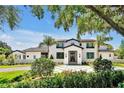 Elegant home featuring manicured landscaping and a circular driveway, framed by a mature tree and lush greenery at 5525 Isleworth Country Club Dr, Windermere, FL 34786