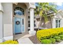 Close-up of the front door with a blue finish and a decorative wreath, complemented by manicured landscaping at 633 Lakehaven Cir, Orlando, FL 32828