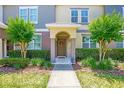 Charming home entrance featuring a decorative wreath on the door and surrounded by lush, green landscaping and trimmed hedges at 7819 Hardenton St, Windermere, FL 34786